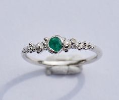 a close up of a ring with a green stone on it's middle finger