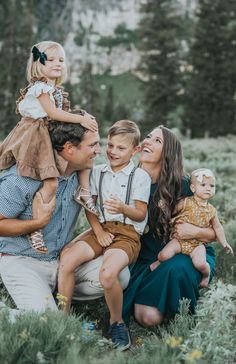 a man and two women sit on a log with three children in front of them