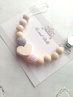 a wooden beaded bracelet with two hearts attached to the clasp on a white card