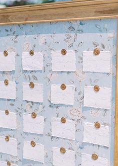 a bulletin board with lots of white paper and gold buttons on it's sides