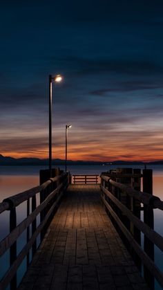 a wooden pier with a light on it at night by the water's edge