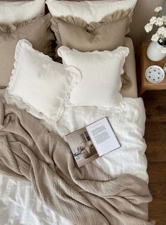 a bed that has some pillows on top of it and a book next to it