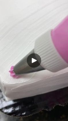 a close up of a pen on top of a piece of paper with pink ink