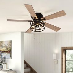 a ceiling fan that is hanging from the ceiling in a room with white walls and wood floors