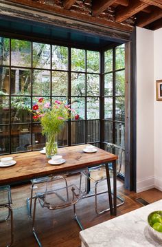 a dining room table with plates and bowls on it in front of large glass windows