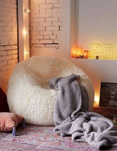 a white bean bag chair sitting on top of a rug next to pillows and blankets