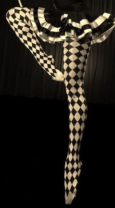 a woman in black and white checkered tights is dancing with her legs spread out