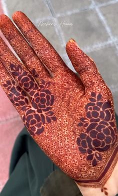 a person holding up their hand with henna on it