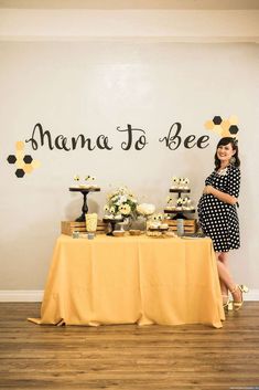 a woman standing in front of a table with cupcakes and cakes on it