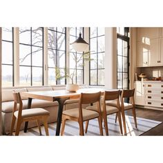 a dining room table with four chairs and a bench in front of large open windows