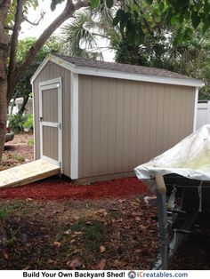 a small shed with the door open next to a tree and some red mulch