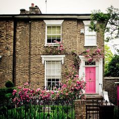 a brick house with pink doors and flowers on it