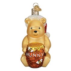 The delightful Winnie the Pooh Old World Christmas 12703 ornament showcases a bear-shaped decoration inspired by the beloved character, adorned with a Santa hat and a honey pot labeled Hunny. The cheerful bear hangs merrily from its gold hanger, adding festive joy to your holiday decor. Christmas Winnie The Pooh, Nutcracker Decor, Christmas Jigsaw Puzzles, Childhood Characters, Old World Christmas Ornaments, Christmas Offers, Halloween Lanterns, Old World Christmas, Famous Books