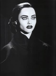 a black and white photo of a woman with dark makeup