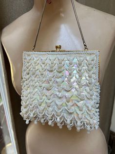 "Darling and perfect off white sequined beaded little bag just right for a bride.  Label inside is Weinstock's British Crown Colony of Hong Kong.  Perhaps used once and like new. Wonderful combination of aurora borealis glimmery sequins in round and rectangular shapes.  Delicate soft pastel gleam as the bag moves. Tiny white seed beads along and around the gold polished frame and little faceted beads dangling from tiny strands of seed beads. Kissing locks. Snake chain strap. Golden beige satin l Vintage White Embellished Bags, Elegant White Sequined Bags, Vintage White Party Bags, White Vintage Party Bag, Vintage White Embellished Evening Bag, Embellished White Clutch Evening Bag, White Sequined Bags For Wedding, White Embellished Evening Bag, White Sequin Bag For Wedding