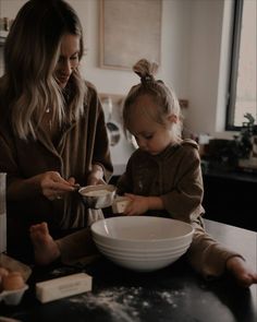 a mother and her daughter mixing together food in a bowl on the kitchen counter top