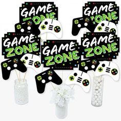 a bunch of game controllers on sticks with some flowers in a vase next to them