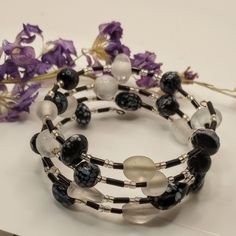 Experience timeless elegance with our stunning white and black glass bead bracelet. Handcrafted with a variety of beads, each piece is unique and versatile, effortlessly complementing any outfit with ease. Adjustable Glass Bracelets With Unique Variations, Elegant Beaded Glass Stretch Bracelet, Elegant Beaded Glass Bracelets, White Glass Beaded Bracelets, White Glass Beaded Bracelets With Round Beads, Elegant Glass Beaded Bracelets With Spacer Beads, Elegant Glass Beaded Bracelets With Large Beads, Black Bohemian Glass Jewelry, Adjustable Black And White Beaded Jewelry