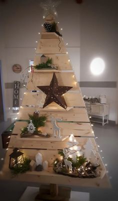 a christmas tree made out of wooden planks with lights around it and decorations on the top