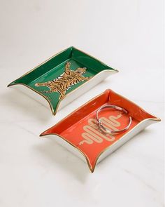 two trays with rings on them sitting next to each other in front of a white background