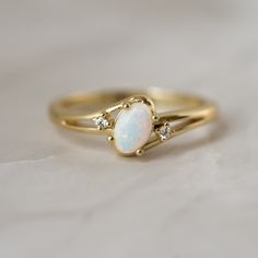 an opal and diamond ring on a white surface