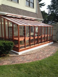 a house that has a brick walkway in front of it and a glass enclosed porch on the side