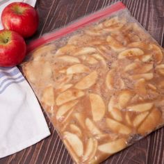 an apple pie sitting on top of a wooden table next to two pieces of fruit