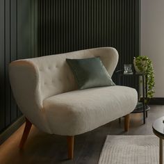 a living room with a white couch and green pillows on the armrests next to a coffee table