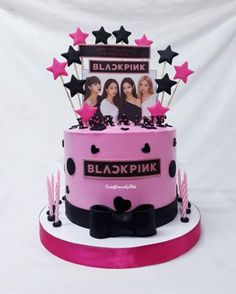 a pink and black birthday cake with pictures on the top, stars and candles around it