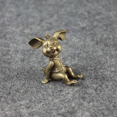 a small bronze dog charm sitting on the ground