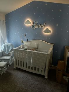 a baby's room decorated in blue and white with stars on the wall, crib and rocking chair