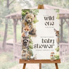 an easel with a baby shower sign on it in front of a forest background