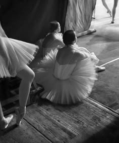 two ballerinas sitting on the floor in front of an audience