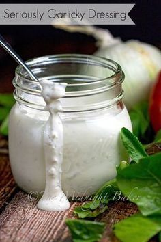 a jar filled with white liquid sitting on top of a wooden table next to vegetables