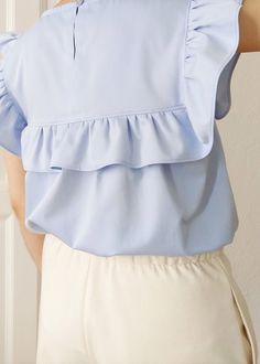 "Fresh as a breath of spring, the Hana ruffle blouse will be your perfect warm-weather wardrobe essential. This relaxed ruffle tunic top is crafted in a lightweight organic cotton fabric with an uplifting and serene sky blue colour that will never go out of style. Blending classic and contemporary style with attention-grabbing accents such as a detailed bib with romantic ruffles, this eco-friendly top will create endless opportunities for your wardrobe. Perfect for just hanging out at home or go Brunch Tops With Ruffle Hem And Ruffled Collar, Solid Color Ruffled Tops For Summer, Solid Ruffled Tops For Summer, Solid Tops With Ruffles For Summer, Cotton Blouse With Flutter Sleeve For Work, Spring Ruffled Collar Blouse For Brunch, Spring Ruffled Collar Top For Brunch, Spring Tops With Ruffle Hem And Ruffled Collar, Spring Brunch Blouse With Ruffled Collar