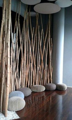 the room is decorated with wood sticks and round cushions, along with white balls on the floor