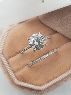 an engagement ring in a box with a fur lining around it and a diamond on the band