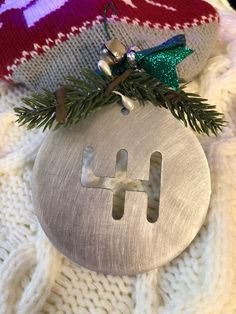 a metal ornament with the letter h hanging from it's side on a sweater