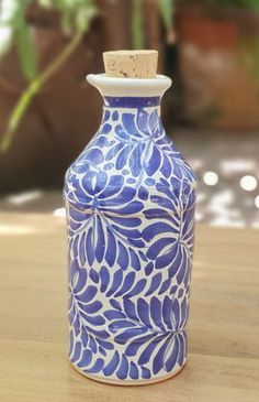 a blue and white vase sitting on top of a wooden table next to a potted plant