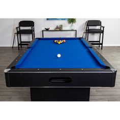 a blue pool table with two chairs in the background and a white ball on it