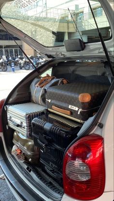 the trunk of a car with luggage in it's back compartment and suitcases stacked on top