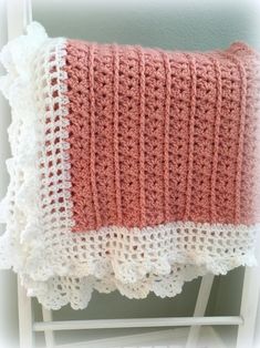 a pink and white crocheted blanket sitting on top of a chair