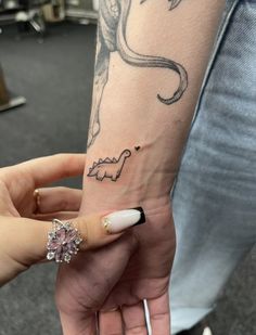 a woman's arm with an octopus tattoo on it and a ring around her finger