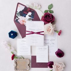 the wedding stationery is laid out on top of each other, with flowers and an ornate frame