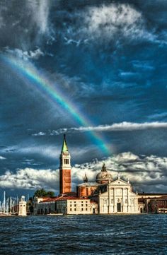 a rainbow in the sky over a large body of water with buildings on both sides