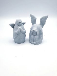 two ceramic figurines sitting next to each other on a white surface with one holding the other's hand