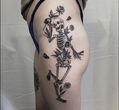 a woman's thigh with a skeleton and flowers tattoo on it