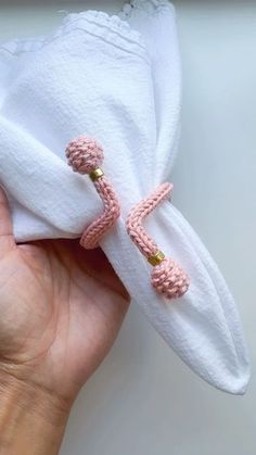 a hand holding a white napkin with pink crocheted handles