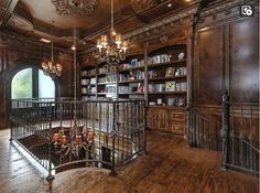 an ornate wooden room with bookshelves, chandelier and spiral stair case