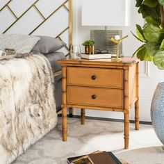 a bed room with a neatly made bed and a plant on the nightstand next to it